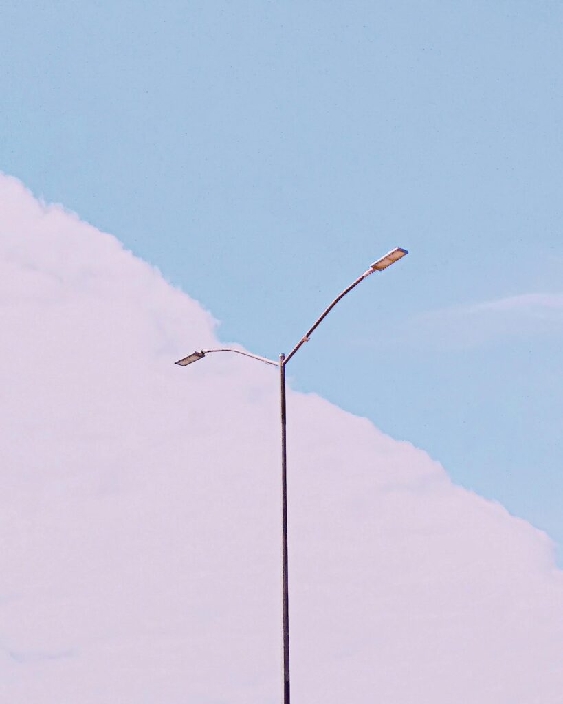 Elegant street lamp stands tall against a pastel blue sky in minimalist composition.