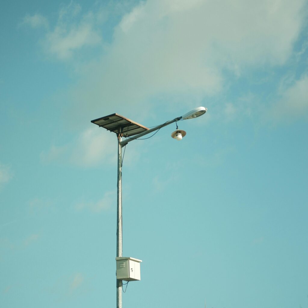 A solar-powered street light set against a clear, blue sky with clouds.
