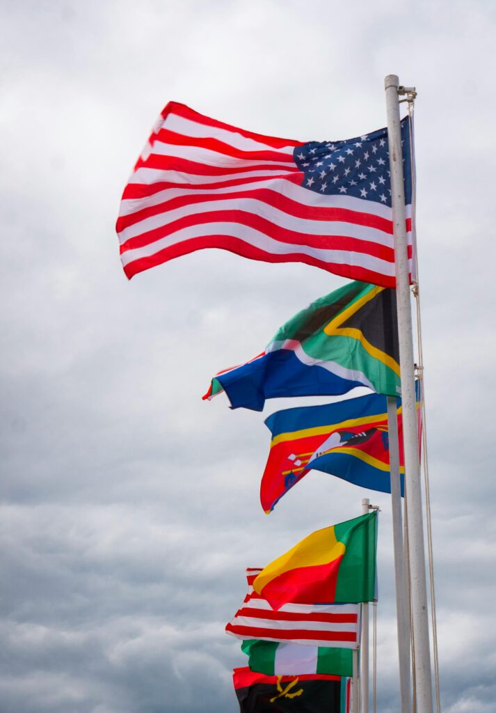 International flags waving on flagpoles against a cloudy sky, symbolizing global unity.