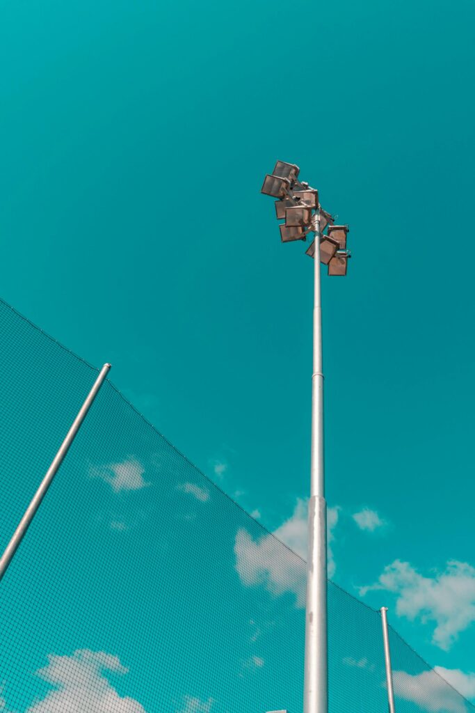 Low angle view of a tall floodlight against a clear teal sky in Oslo, Norway.