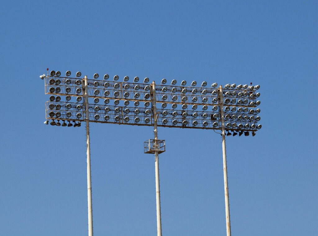 Tall stadium floodlights towering against a clear blue sky, perfect for outdoor sports lighting visuals.