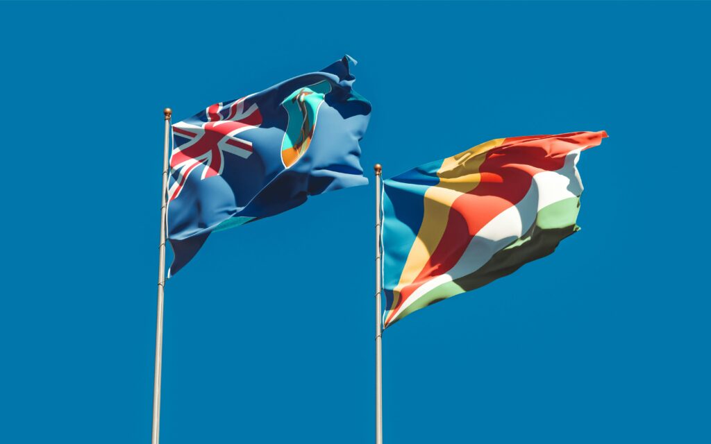 National flags of New Zealand and Seychelles waving against a vibrant blue sky, symbolizing national identity and unity.