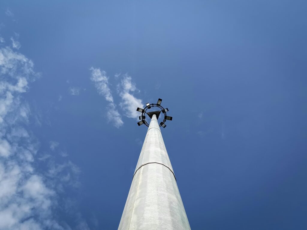 A striking low-angle photograph of a modern street light set against a vivid blue sky with scattered clouds.